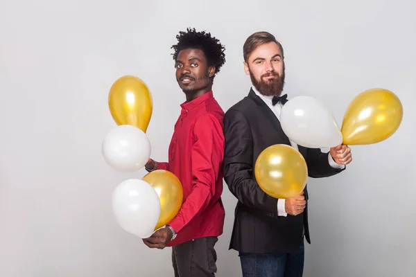 Freunde, die Rücken an Rücken stehen, in die Kamera schauen und — Stockfoto