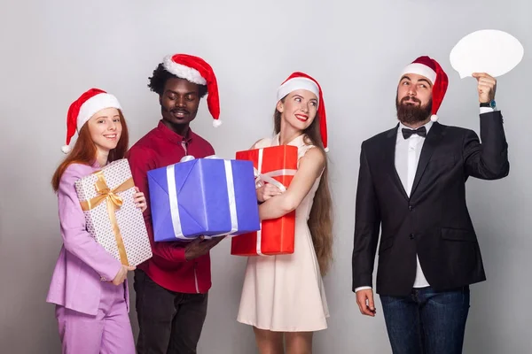 Homme bien habillé regardant loin avec perplexité et visage rêveur, ses amis debout près et tenant boîte cadeau. Prise de vue. Fond gris — Photo