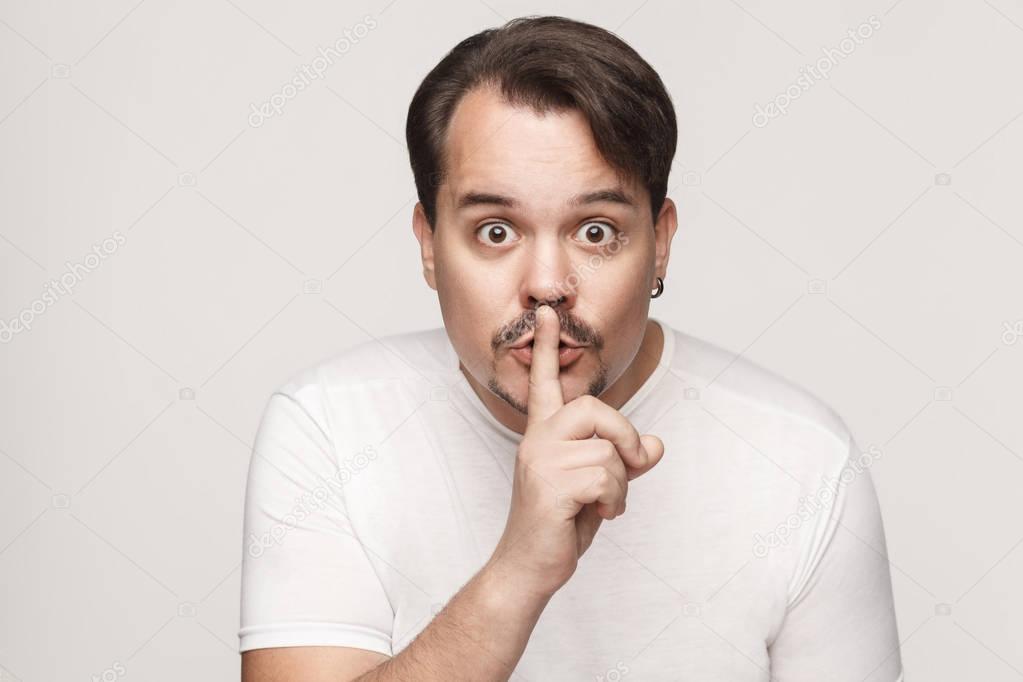 Shh sign. Man with big eyes looking at camera with silent sign. 
