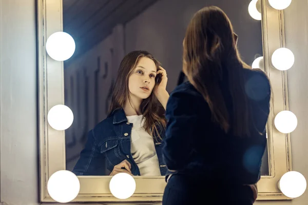 Jovem bela mulher sexy olhando em um espelho, tocando seu hai — Fotografia de Stock