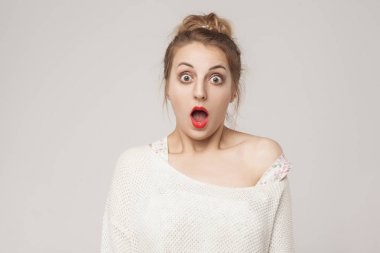 Hayretle sarışın açık ağız ve çığlık sürpriz yüz. Atış, arka planı gri studio
