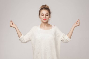 Blone genç yetişkin kadın kapalı, sakin ol ve youga asana yapıyor. Atış, arka planı gri studio