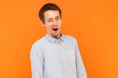 Mavi gömlek, wink kamera duygusal iş adamı. Kapalı atış, turuncu arka plan