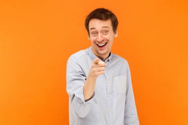 Hey siz! Kamera ve dişlek gülümsemek mutluluk adam işaret parmağı. Atış, turuncu arka plan stüdyo