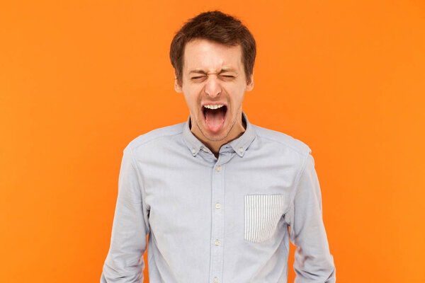 Man closed eyes and tongue out. Studio shot, orange wall