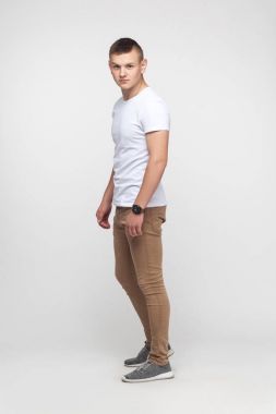 Gri duvara yakın duran ve kameraya bakarak tam yükseklikte genç çocuk. Stüdyo vurdu