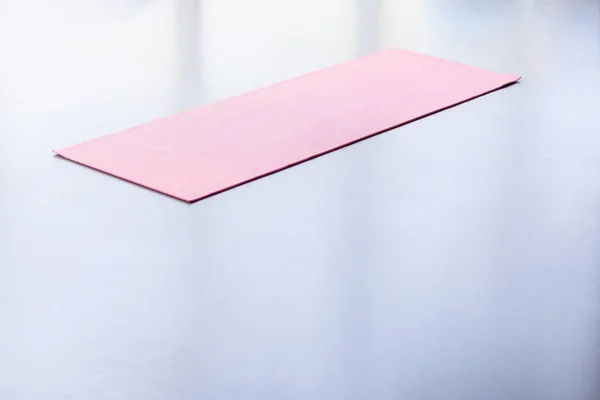 pink yoga mat lying on gray floor