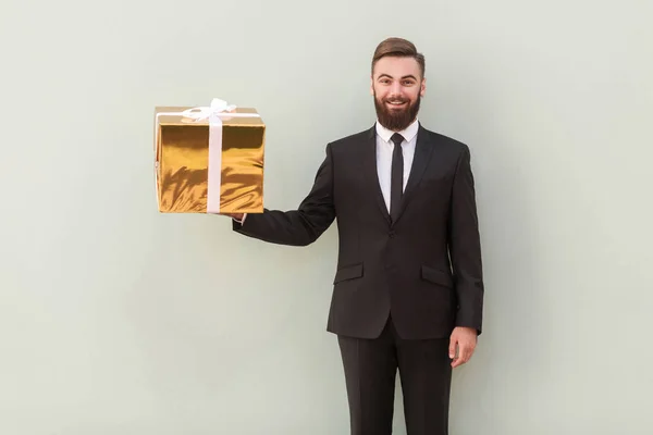 Lachende Baas Bedrijf Gouden Geschenkverpakking Grijze Achtergrond — Stockfoto
