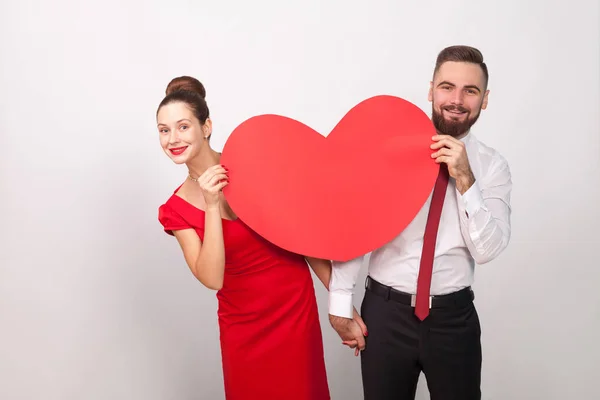 Attraktives Paar Das Hinter Dekorativem Herzen Auf Grauem Hintergrund Hervorblickt — Stockfoto