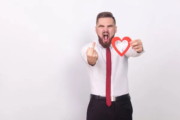 Hombre Enojado Sosteniendo Corazón Mostrando Signo Odio Sobre Fondo Gris — Foto de Stock