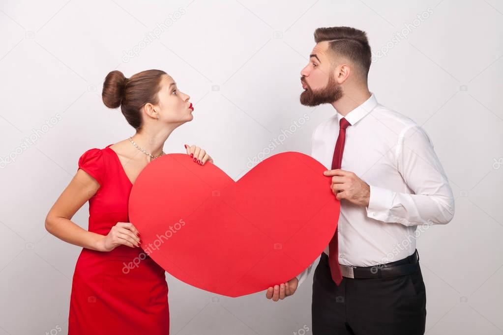 couple holding heart and sending each other air kiss on gray background, valentines day concept 