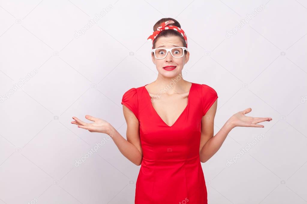confused woman in red dress with divorced hands looking at camera on gray background
