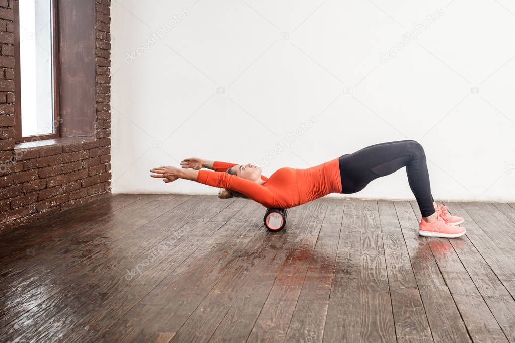 woman doing spine massage with foam roller 