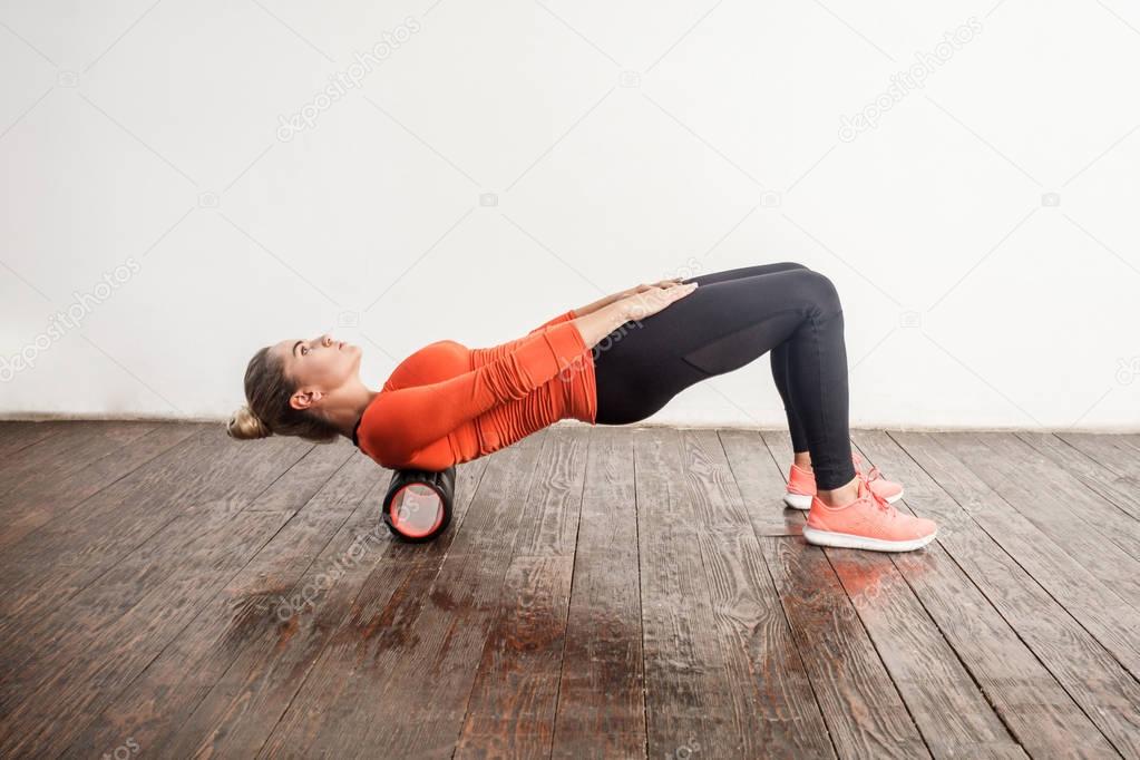 woman doing spine massage with foam roller 