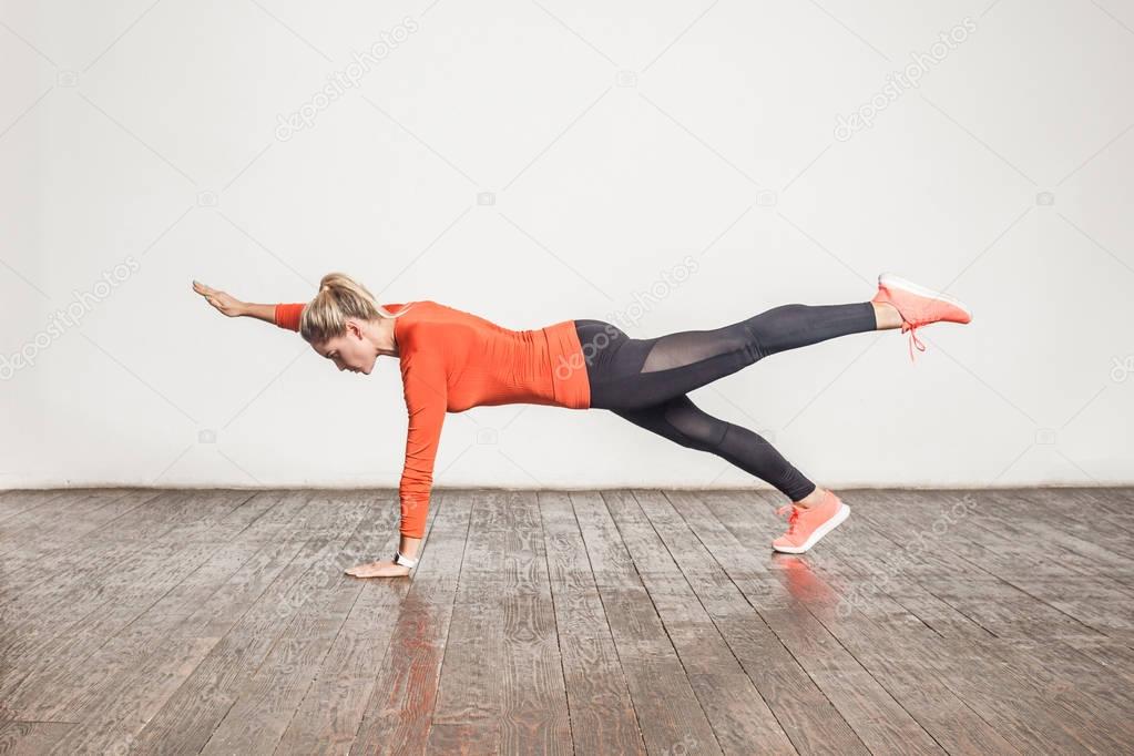 blonde sporty woman doing plank in loft interior room 