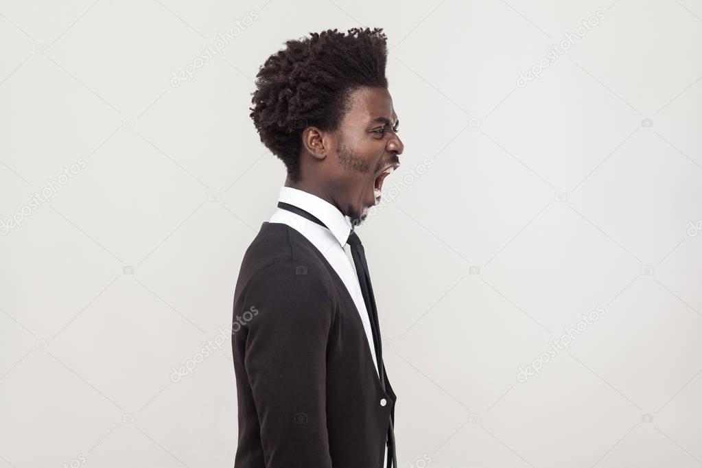 profile view of angry african american man shouting on gray background