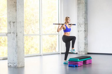 Halter çubuk tutarak ve adım platformda pratik sportif kadın 