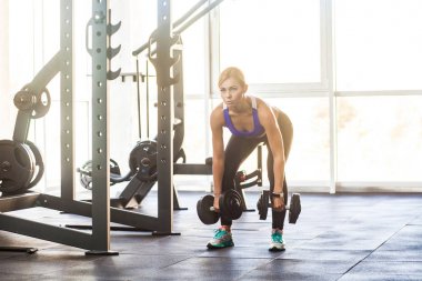 sarışın kadın spor salonunda dumbbells ile devirme