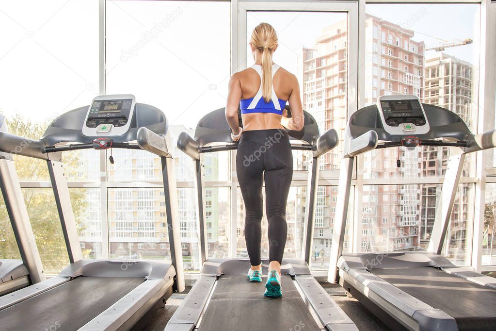 active athletic woman with perfect body jogging on racetrack in  morning