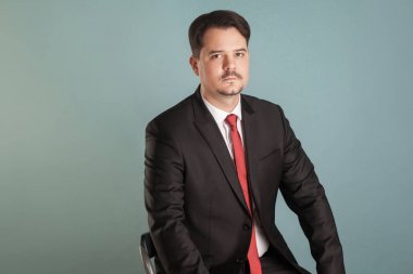 sandalyede oturan ve üzerinde açık mavi renkli kameraya bakarak dalgın işadamı portresi 