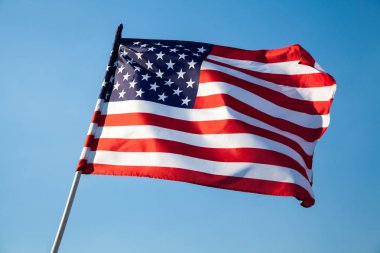Amerikan bayrağı mavi gökyüzü arka plan üzerinde sallayarak  