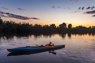 Sportif adam günbatımında ormanıyla çevrili nehir kanosu 