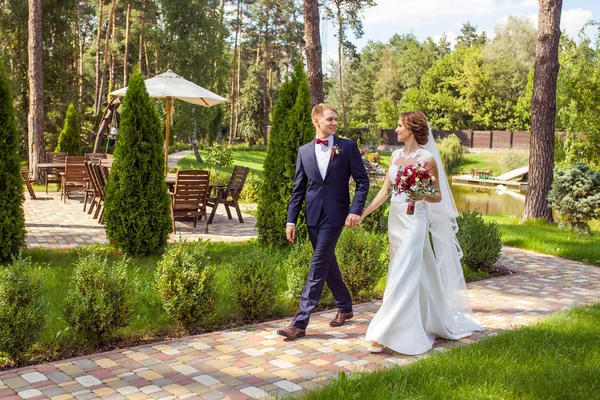 Feliz Recém Casados Mãos Dadas Caminhando Passarela Parque Verão — Fotografia de Stock