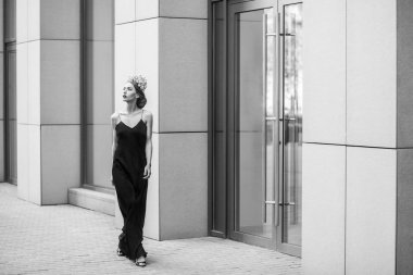 çiçek taç ve uzun Abiye Caddesi üzerinde Binası yakınında yürüyüş giyen zarif kadın 