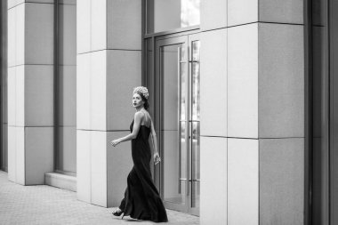 çiçek taç ve uzun Abiye Caddesi üzerinde Binası yakınında yürüyüş giyen zarif kadın 