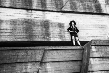 Ahşap inşaat bel ayakta eller ile karanlık giysili şık kadın 