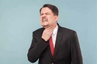 businessman in suit touching throat on light blue background, uncomfortable pain in throat concept  clipart