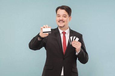 banka kartları açık mavi renkli üzerinde tutan takım elbiseli mutlu işadamı