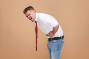 unhappy businessman in half from pain in belly on light brown background, stomach pain concept  clipart
