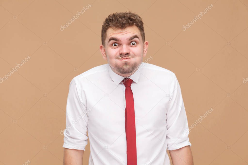 portrait of handsome funny man with big eyes looking at camera on light brown background