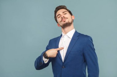 portrait of proud  businessman looking at camera and pointing finger at himself on light blue background, concept of richly and success business people  clipart