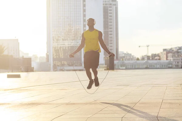 sporty african american jumping on jump rope at street, concept of boxer training before competitions