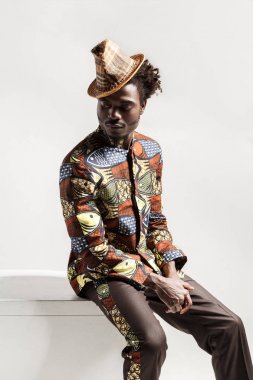 Afro-Amerikan yakışıklı beyaz arka plan üzerinde izole küp üzerinde oturan Ulusal Kongo tarzda giyinen