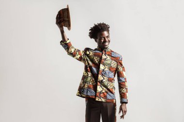 Pozitif Afro-Amerikan modeli gri arka plan üzerinde şapkalı el kadar yükselterek