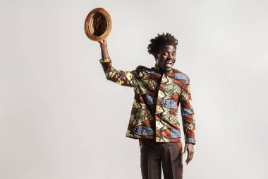 komik Afrikalı-Amerikalı adam dişlek gülümseyen ve şapka ile el kadar yükselterek kameraya bakıyor 