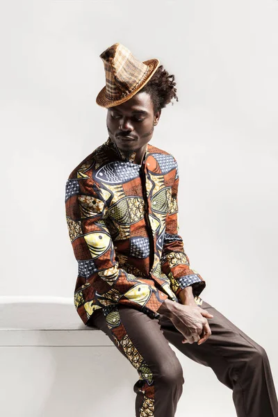 Afro-Amerikan yakışıklı beyaz arka plan üzerinde izole küp üzerinde oturan Ulusal Kongo tarzda giyinen
