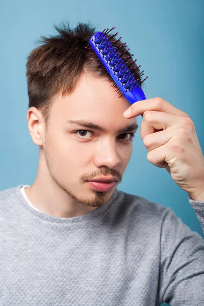 Healthy hair. Portrait of brunette man combing his hair, showing — Stock Photo, Image