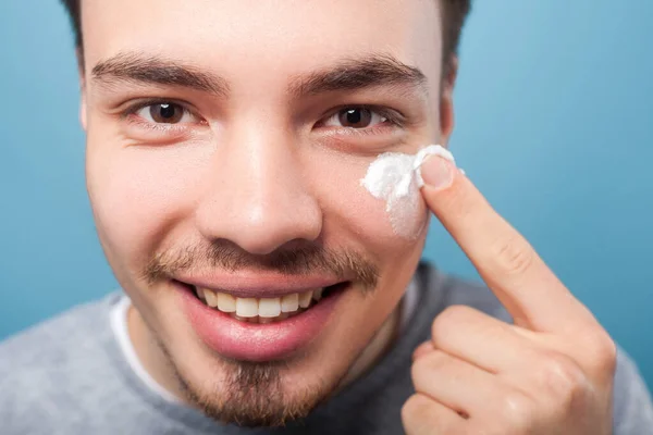 Male skincare cosmetics. Portrait of happy handsome man applying — Stock Photo, Image