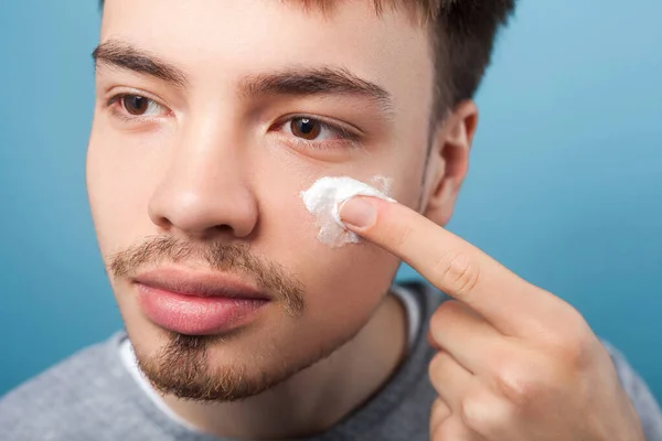 Male beauty and skincare. Portrait of young handsome man applyin — Stock Photo, Image