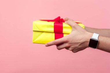 Closeup of young male hands giving yellow gift box with red ribb clipart