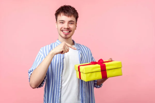 Egy fiatal, boldog barna hajú férfi portréja, aki az ajándékdobozra mutat. i. — Stock Fotó