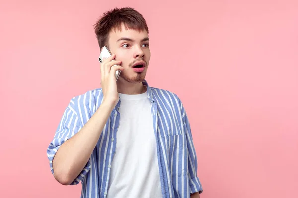 Πορτρέτο του έκπληκτος νεαρός καστανά μαλλιά μιλώντας στο τηλέφωνο. — Φωτογραφία Αρχείου