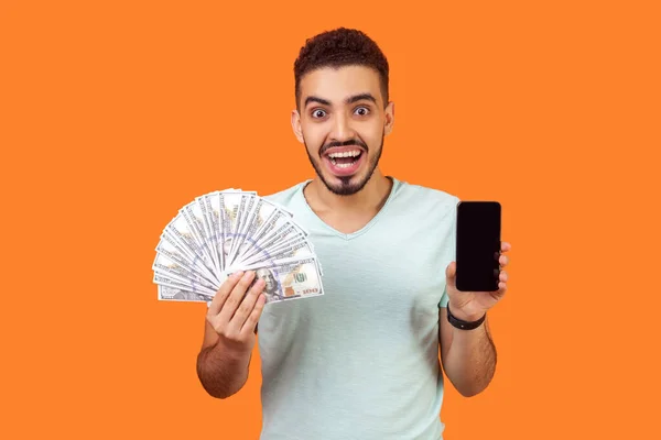 Pago en línea. Retrato de un hombre extremadamente feliz sosteniendo el dinero y — Foto de Stock