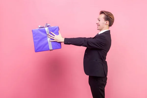Fogd ezt az ajándékot! Oldalnézet boldog nagylelkű ember kinyújtja ajándék — Stock Fotó