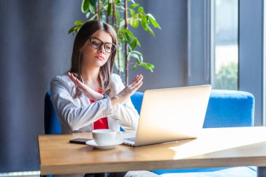 Kapalı. Sona geldik. Gözlüklü ciddi bir genç kadının portresi. Bilgisayarındaki ekrana bakıyor ve X işaretini elleriyle gösteriyor. İç mekan stüdyo çekimi, kafe, ofis geçmişi..