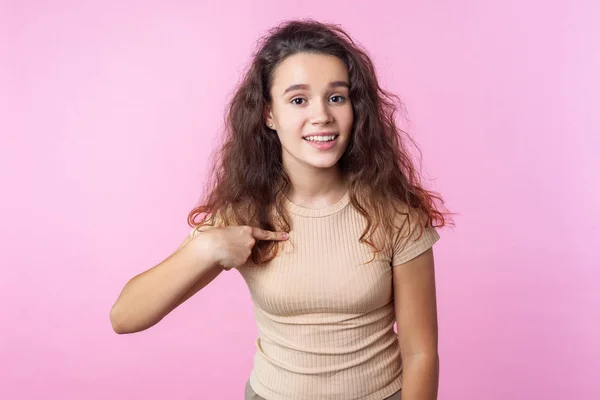 Retrato de la encantadora adolescente sonriendo a la cámara y apuntando a un —  Fotos de Stock